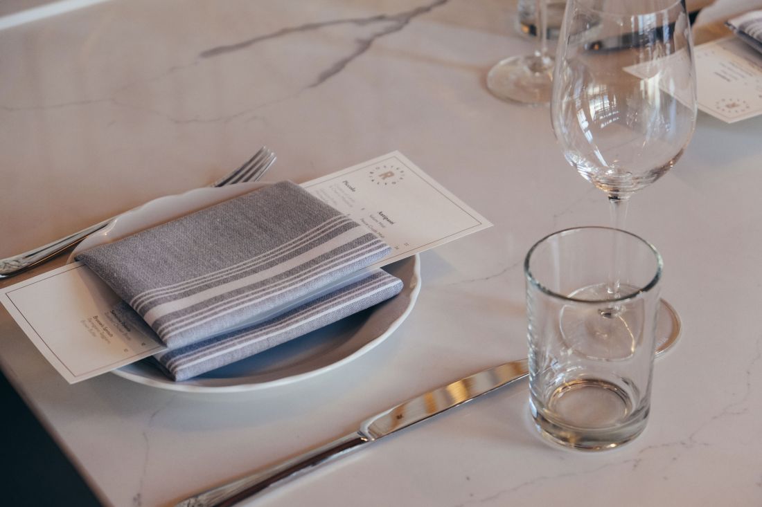 Place setting on a marble table top with Osteria Rialto menu